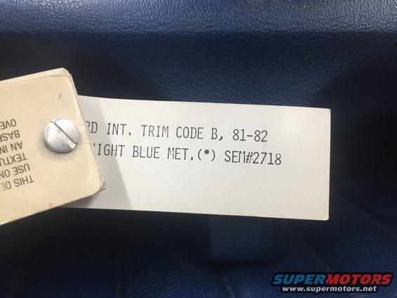 Close-up of a trim tag showing 'FORD INT. TRIM CODE B, 81-82 LIGHT BLUE MET. SEM#2718' against blue upholstery