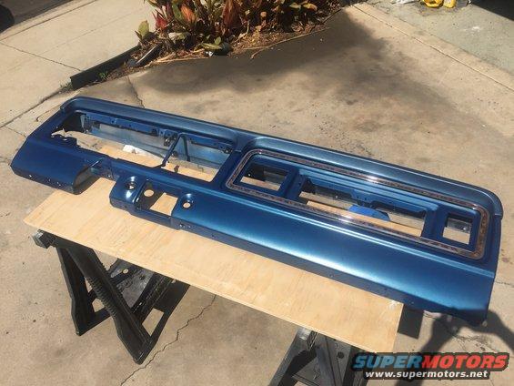 Blue painted dashboard trim panel with chrome accents, resting on sawhorses