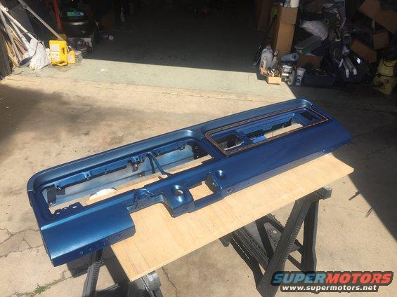 Blue painted dashboard section resting on sawhorses outdoors
