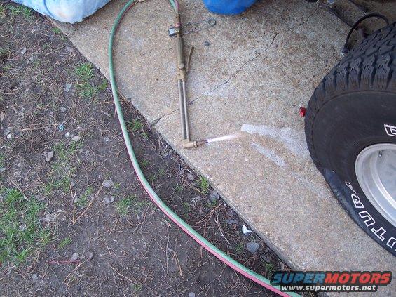 Oxy-acetylene cutting torch spraying sparks onto concrete next to a tire