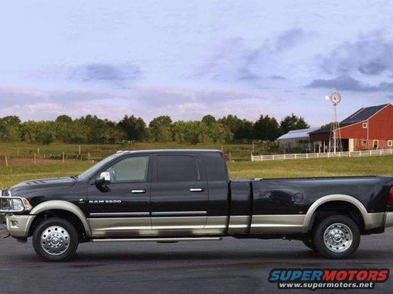 Black Dodge Ram 3500 pickup truck, side view. Farm buildings and a windmill in the background
