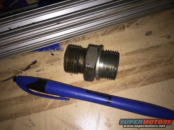 Metal pipe fitting with male threads on both ends, next to a blue pen