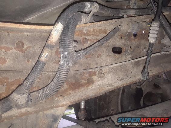 Close-up of a rusty truck frame with corrugated wiring harnesses and connectors