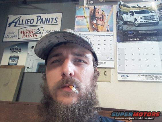 Man smoking cigarette in front of calendars and advertisements