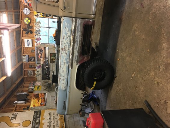 1967 Ford F-250 truck body in primer, side view, undergoing restoration in a garage