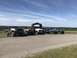 1989 Ford Bronco - Several modified off-road vehicles are parked together in a rural setting on a sunny day.