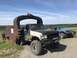1989 Ford Bronco - Two off-road vehicles are parked outdoors on a sunny day, with one truck a massive, rusty metal attachment.