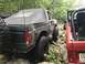 1989 Ford Bronco - A black 1989 Ford Bronco with a soft top is seen off-roading on a rocky path, with a red Jeep visible to its right.