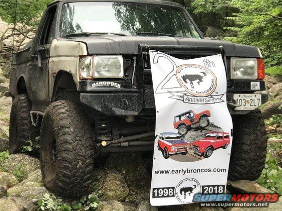Modified Ford Bronco with large tires and a banner advertising earlybroncos.com
