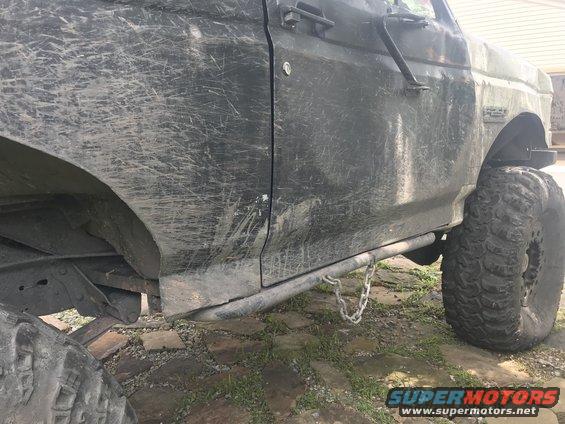 Dark SUV side with mud splatter, rock sliders, and large off-road tires