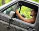 1989 Ford Bronco - A man drives a heavily mud-splattered SUV, with the side mirror and interior visible.