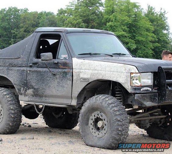 Mud-splattered black Ford Bronco with oversized tires and a lifted suspension