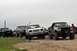 1989 Ford Bronco - Several Ford trucks and SUVs, including a Bronco and F-150, are parked together on a dirt area.