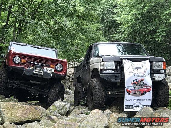 Red Bronco and black Bronco on rocks, banner on black Bronco shows "earlybroncos.com" and "1998 2018"