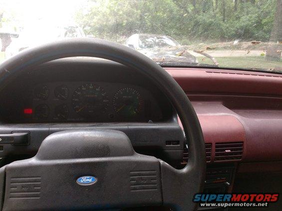 1989 Ford Probe interior showing dashboard, steering wheel with Ford logo, and gauges. Another car is visible through the windshield