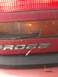 1989 Ford Probe - The 'PROBE' emblem is visible on the rear of a red vehicle, near a damaged taillight assembly.