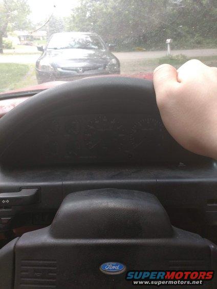 View from driver's seat looking at dashboard and steering wheel; another car is visible through the windshield