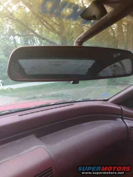 Interior rearview mirror and part of the dashboard. Text is visible on the mirror