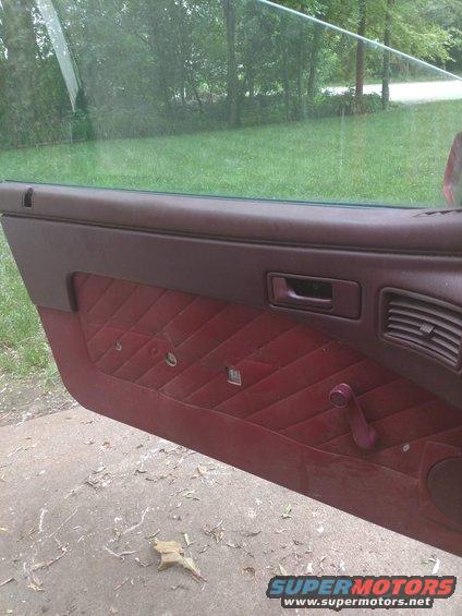 Maroon quilted interior door panel with manual window crank and vent