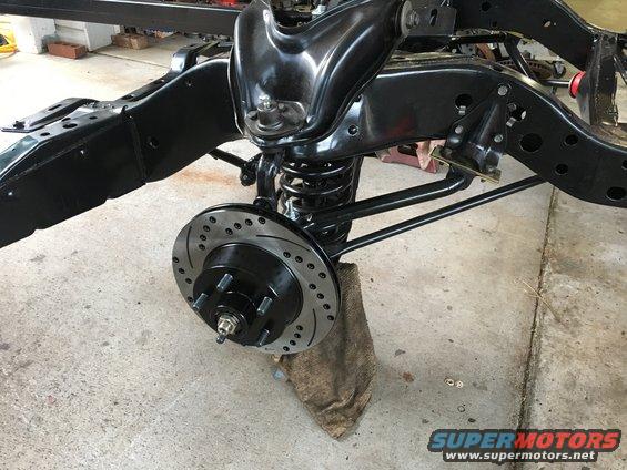 Front suspension assembly with drilled disc brake rotor and caliper