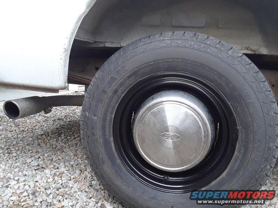 Close-up of a Ford van's rear wheel, hubcap, and exhaust pipe