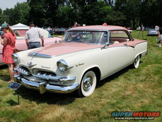 Two-tone pink and white 1955 Dodge La Femme parked on grass at a car show