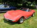 1971 Ford Ranchero - A red convertible sports car with a black interior is parked on a grassy lawn next to a blue coupe.