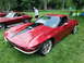1971 Ford Ranchero - A red 1965 Chevrolet Corvette Sting Ray is parked on grass, with another classic Corvette in the background.
