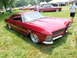 1971 Ford Ranchero - A custom red coupe with a distinctive grille and chrome wheels sits on display at an outdoor event.