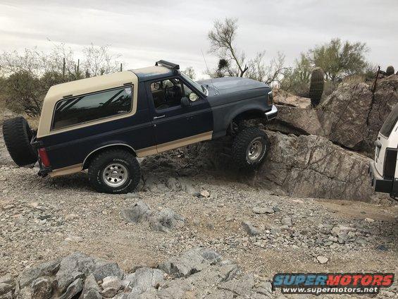 Dark blue and tan 1991 Ford Bronco climbing rocks