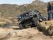 1991 Ford Bronco - A lifted Ford Bronco navigates a rocky desert terrain with a driver and onlookers present.