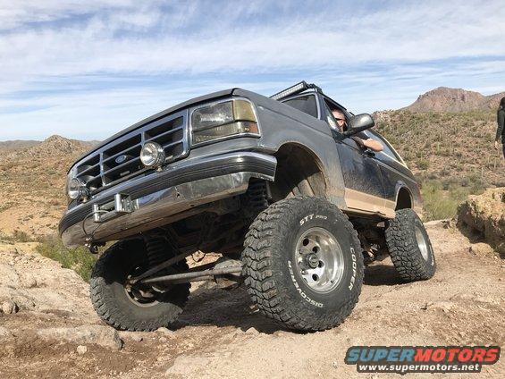 Gray Ford Bronco with lifted suspension and off-road tires driving on a rocky desert trail