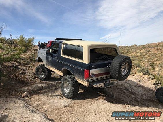1991 Ford Bronco rear view, blue and tan, with spare tire on dirt trail