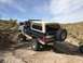 1991 Ford Bronco - This 1991 Ford Bronco is seen from the rear, navigating a rocky off-road trail with other vehicles in the background.