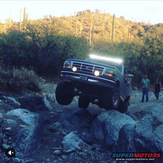 Black Ford Bronco with light bar climbing rocks