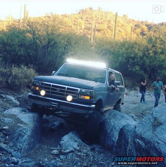 1991 Ford Bronco navigating rocky terrain with a light bar on the roof
