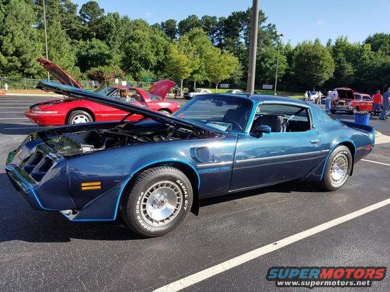 Blue 1977 Pontiac Firebird Trans Am with hood open, parked next to a red car with hood open