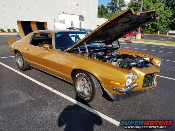 Gold 1970s Chevrolet Camaro with hood open, black racing stripes on trunk lid
