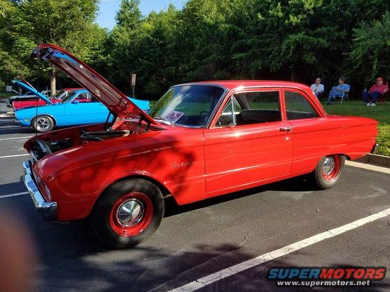 Red 1960 Ford Falcon sedan with hood open, parked next to a blue car