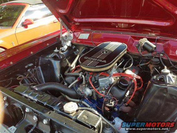 Red car engine bay with a black Cobra air cleaner and an orange car in the background