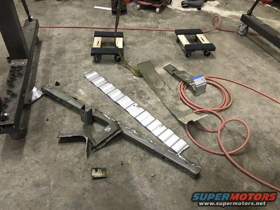 Metal frame parts and a coiled hose on a concrete floor