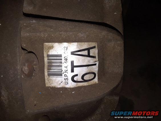 Gray metal transfer case part with a white label showing a barcode and text '6TA U.S.P.N.4, 440, 042'