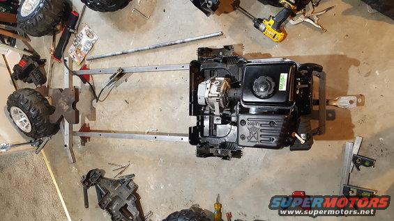 Go-kart frame with engine and wheels, tools scattered around
