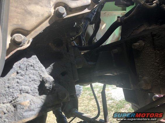 Close-up of dirty engine and suspension parts of a vehicle, with green paint visible