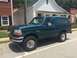 1996 Ford Bronco - A green 1996 Ford Bronco is parked on a street in front of a building.