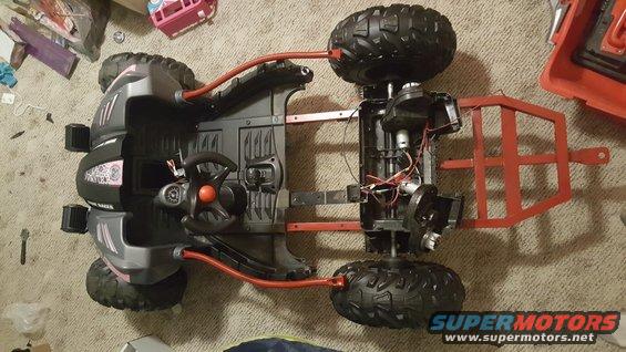 Underside view of a toy ATV chassis with exposed wiring and motors