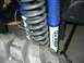 1989 Ford Bronco - Close-up of Pro-Comp ES3000 shocks and a large off-road tire, part of a vehicle's front suspension system.