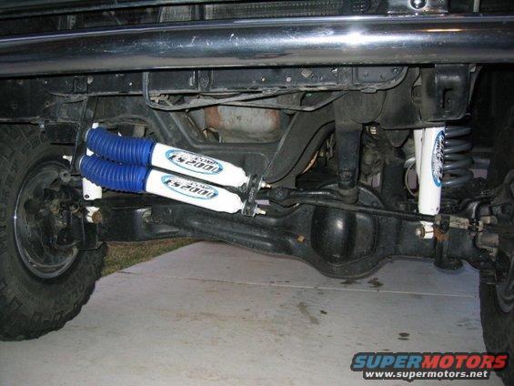 Rear axle with dual blue-booted shocks and one white shock absorber installed