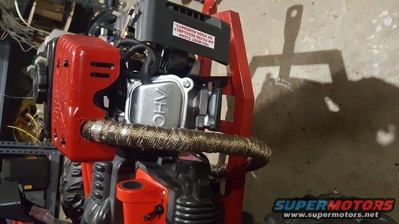Engine with red casing and exhaust wrap. Text on black sticker reads: YOU MUST CLEAN AIR FILTER REGULARLY OR VOIDS WARRANTY