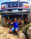 1995 Ford Bronco - A man poses in front of a lifted Ford truck, showing off its off-road capabilities.